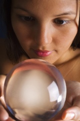 A young Asian woman looks into a crystal ball